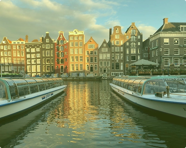 Panoramisch avondzicht op het historische stadscentrum van Gent, met verlichte middeleeuwse architectuur, kerktorens en een reuzenrad onder een bewolkte lucht.